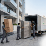 House movers in Dubai Marina handling boxes and furniture near a high-rise tower.